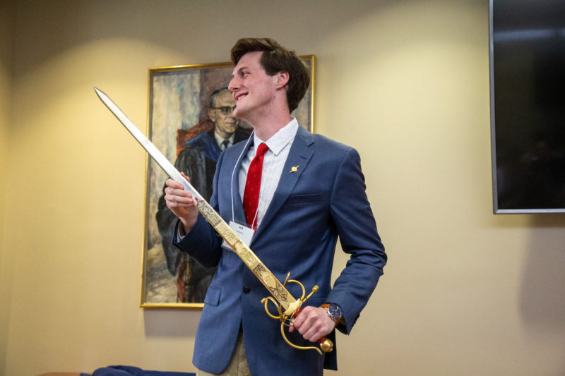 Rick Smallshaw '23 holds a sword during his presentation about Geoffrey Chaucer's use of the color red.