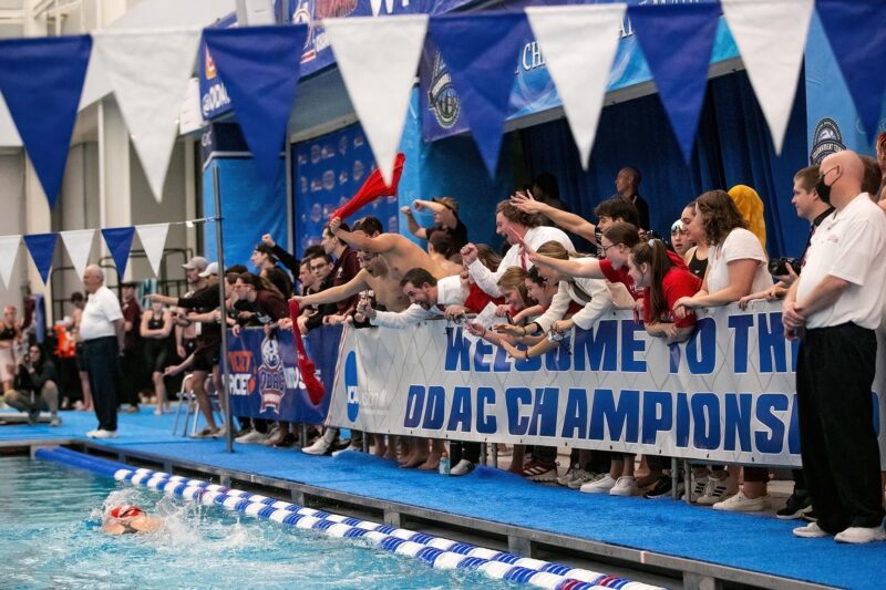 Swimmers hold a banner above a pool cheering