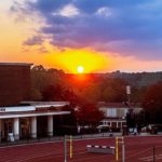 A brick athletic building and a track at sunset