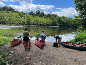 Four students with four canoes on the James River.