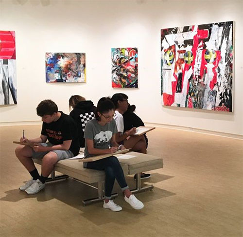 A group of students study on a bench at the Daura Museum.