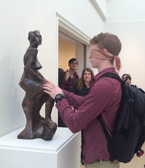 A blindfolded student touches a sculpture at the Daura Museum.