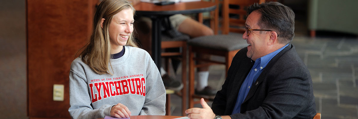 A University of Lynchburg students speaking with her advisor while seated at a table