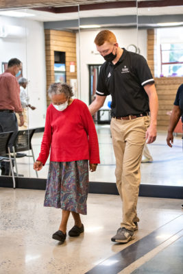 A student leads an older woman through an exercise