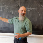 A professor teaching in front of a blackboard