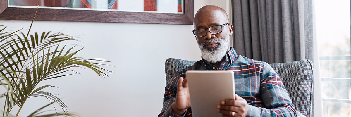 An elderly gentleman reading on a tablet