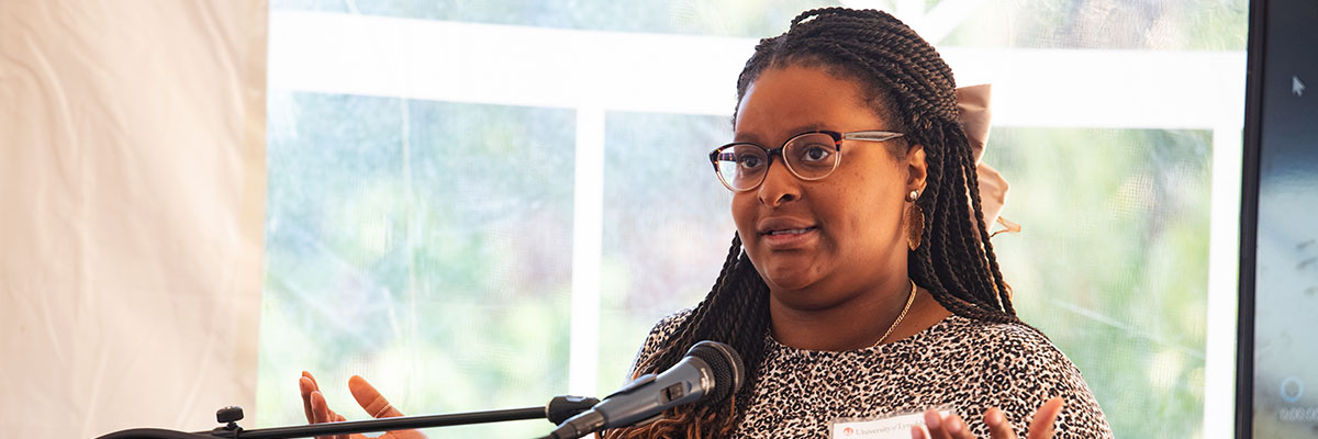 A black University of Lynchburg alumna speaking at a podium