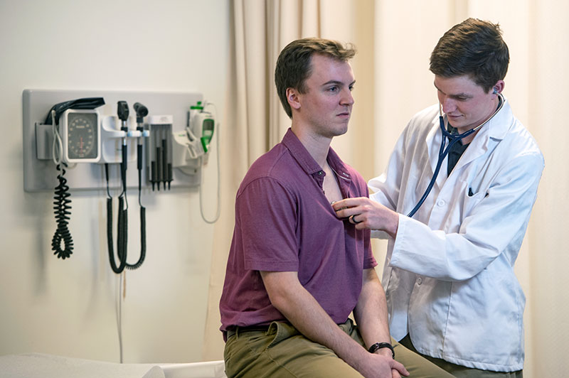 A Master of PA Medicine student listens to a patient's heart with a stethoscope