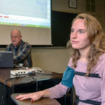 A student is sitting in a chair while her professor is giving her a polygraph test