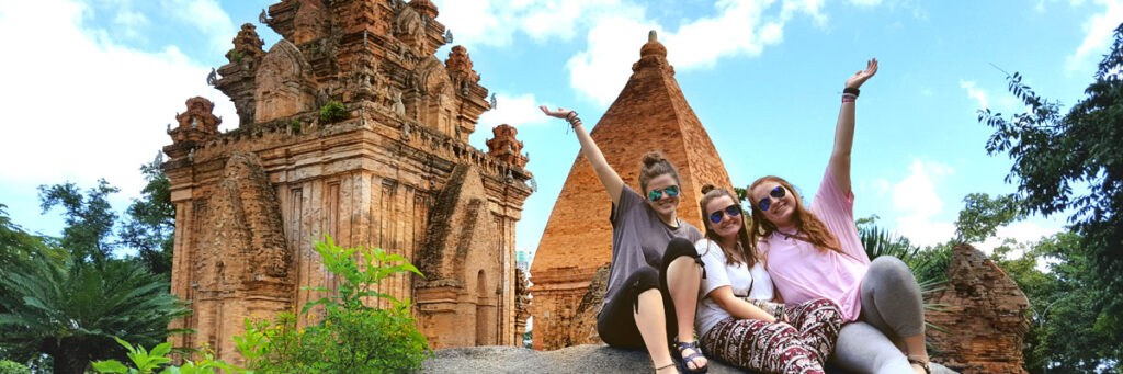 Three students posing in front of a cultural building abroad