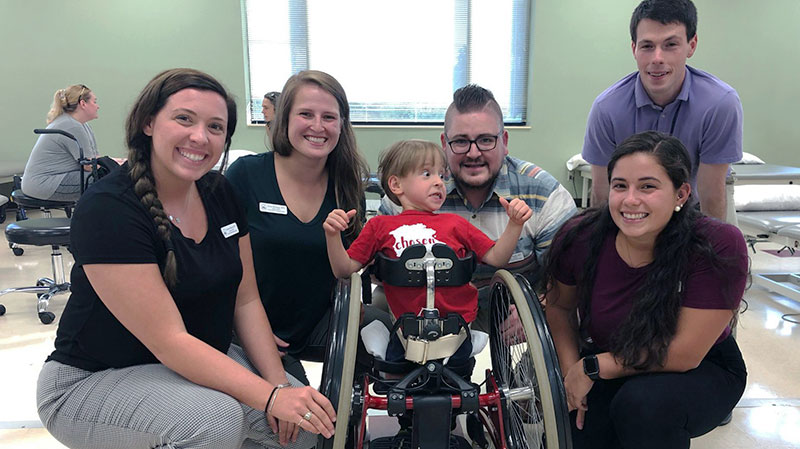 DPT students surrounding a young boy in a wheelchair