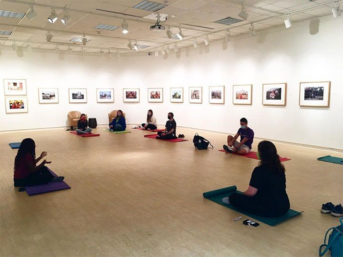 Meditating students sit on the floor of an art museum exhibit.