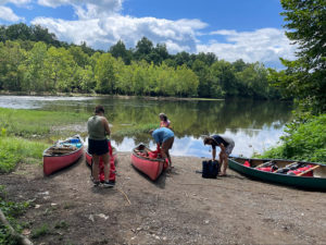 Four students with four canoes on the James River.