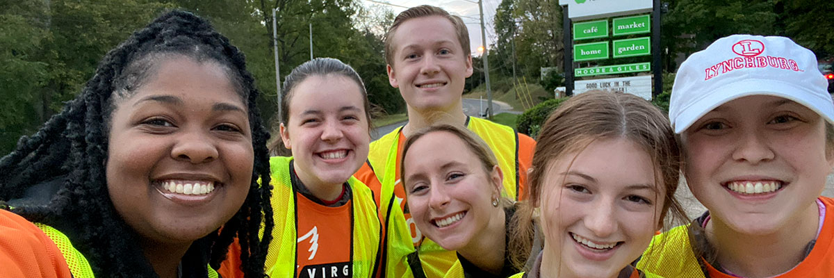 Six students taking a selfie wearing yellow safety vests.