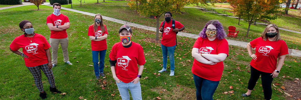 Seven first-generation students stand outside wearing their "I'm First!" t-shirts.