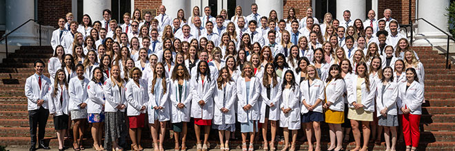 Group of students pose in their long white coats.