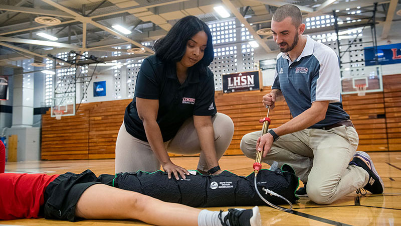 Two students in the Master of Science in Athletic Training program apply an inflatable cast to an athlete.