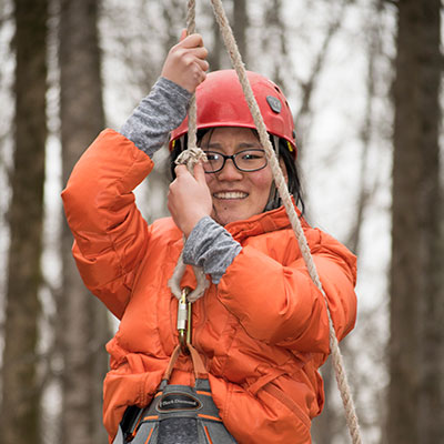 A student hanging from a rope on the ropes course.