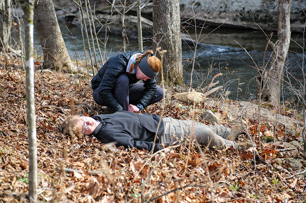 A student practices wilderness first aid on a volunteer.