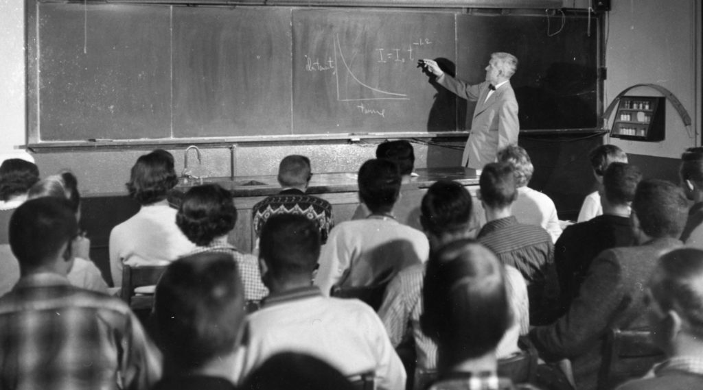 Dr. Rosser at a chalkboard as people listen.