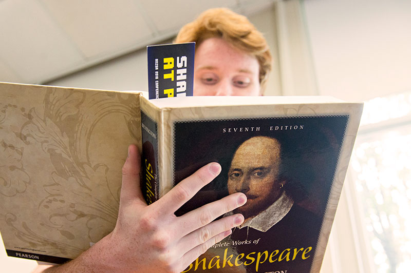 A male student reading a book by Shakespeare
