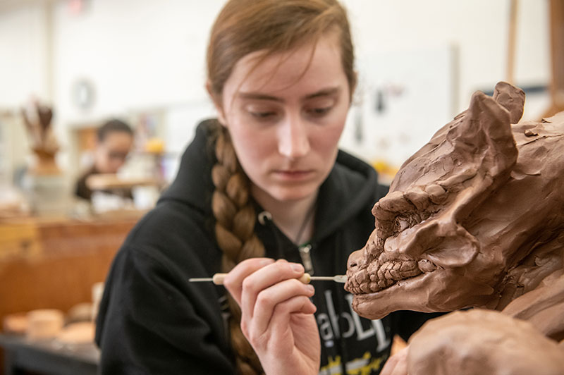 A female student working on a dragon sculpture