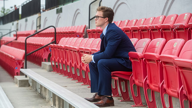 A Master of Business Administration (MBA) sits on bleachers in a sports stadium.