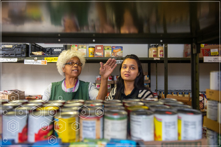 Master of Public Health Jobs - Two women stand among shelves of canned food.