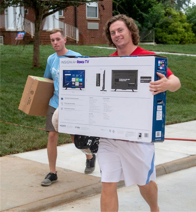 Two students carry boxes on move-in day.