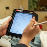 Hands holding a tablet in a hospital room