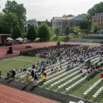 chairs, a stage and people on an athletic field
