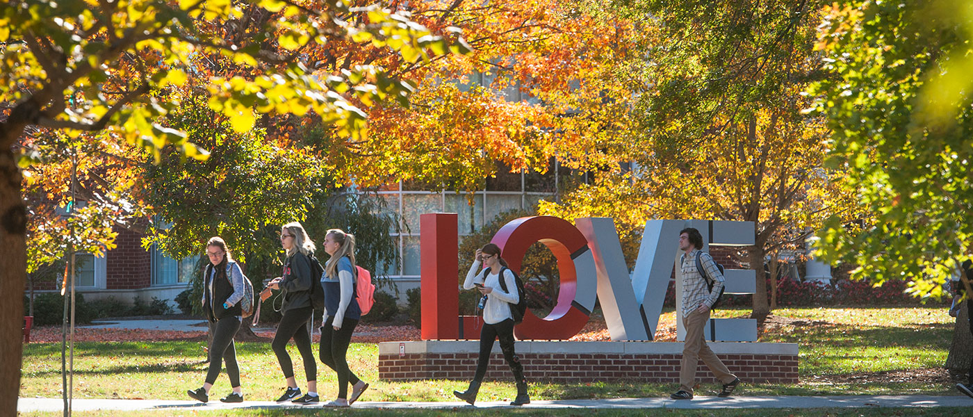 Students walking on the Dell in front of the Love sculpture