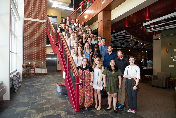 A group of students pose on a stairwell.