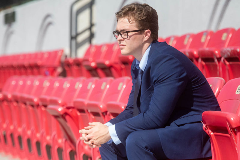 Sport Management MBA- a student in a suit sitting on red bleachers