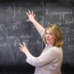 A professor teaching in front of a blackboard