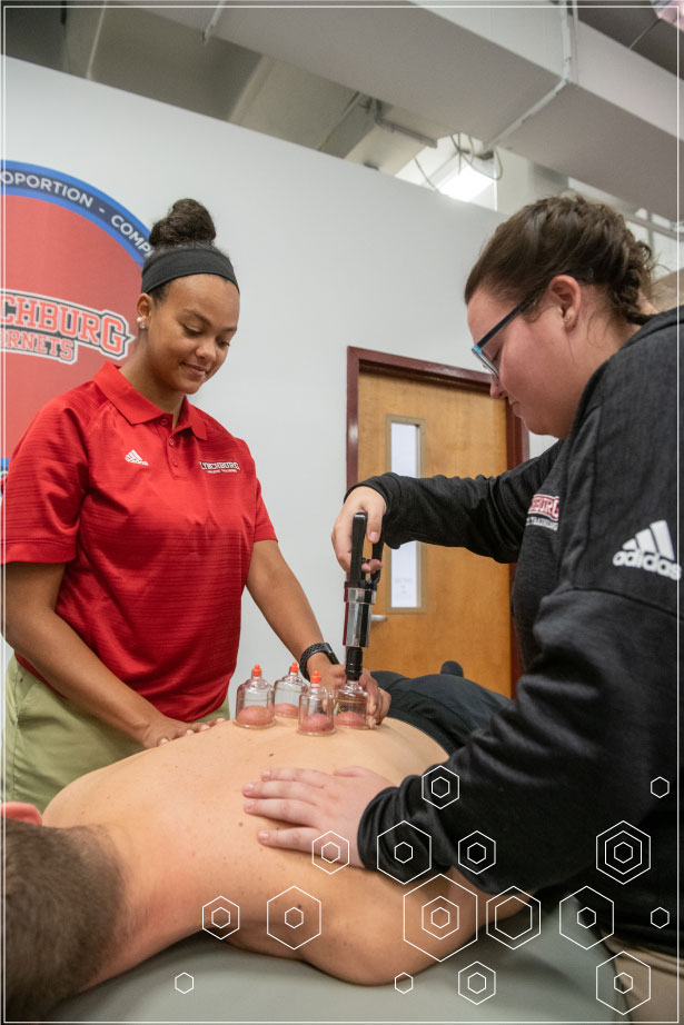 Two athletic training students practice cupping in Lynchburg's top athletic training graduate program.