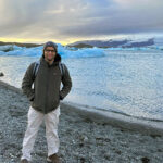 Vedant Patel standing outdoors near a body of water during a trip to Iceland